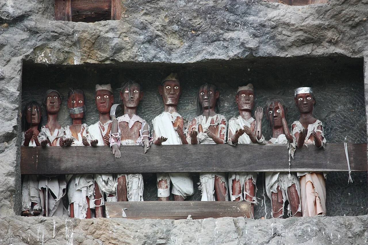 Carved tau-tau figures standing in a rock gallery at Lemo