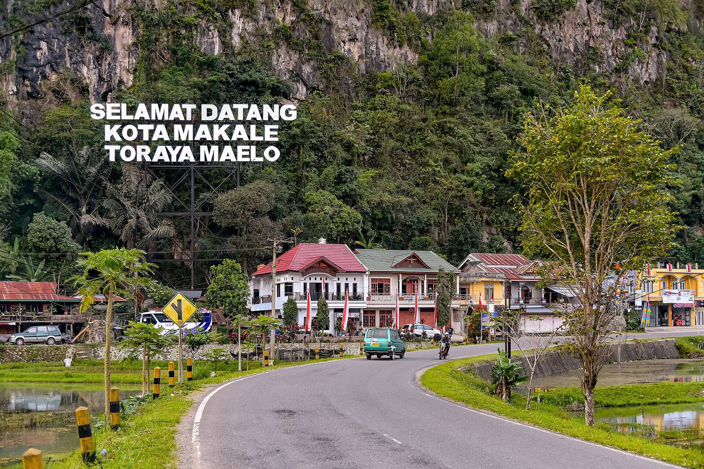 A curving road and civic buildings beneath the cliff at the entrance to Makale