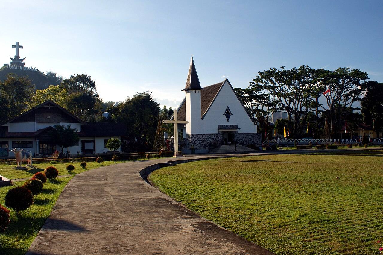 A white church with a steep roof beside the lawn in central Rantepao