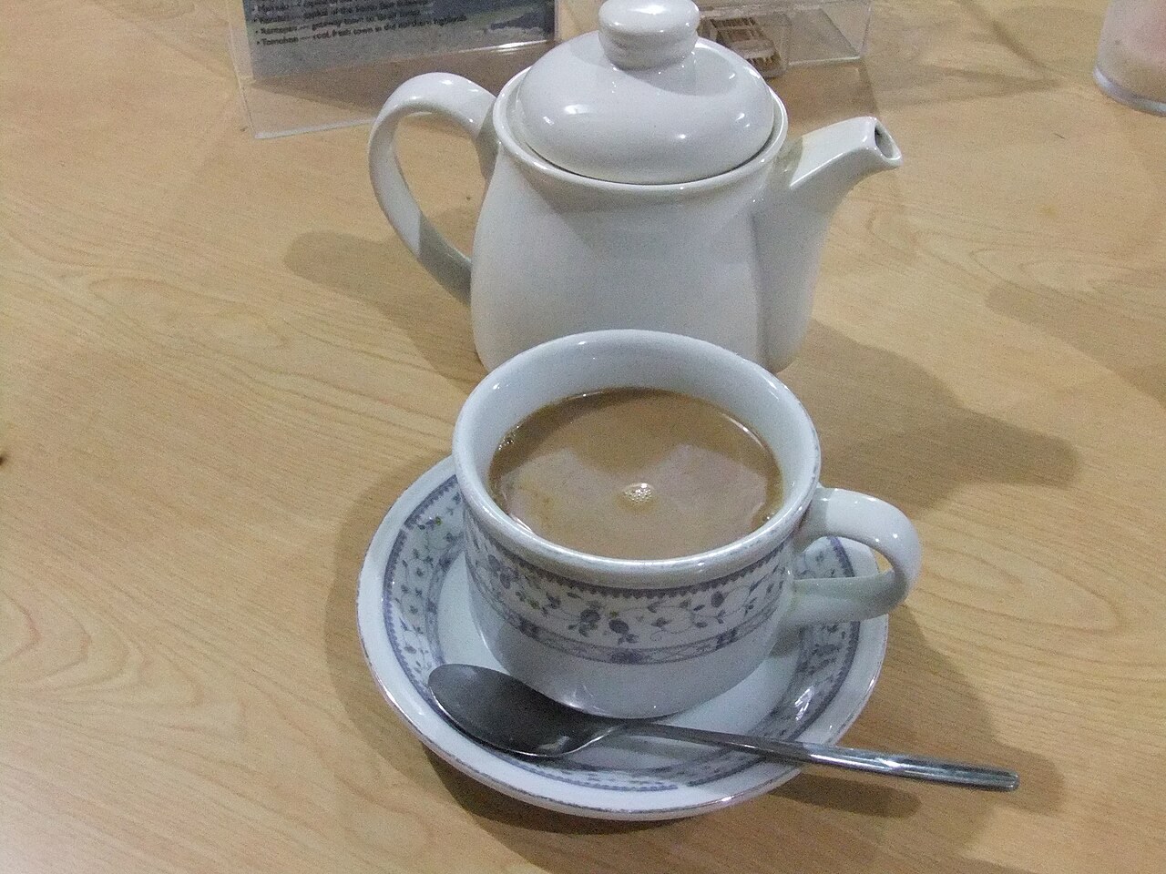 A cup of coffee with a white pot on a table in Rantepao