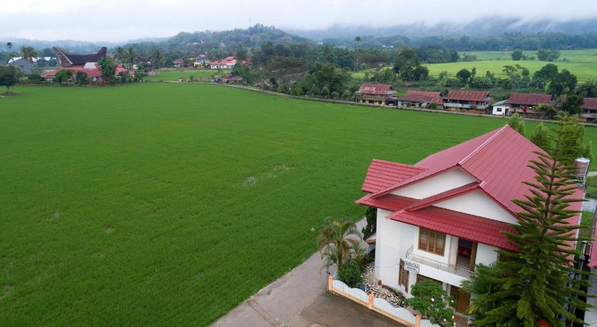 Rosalina Homestay beside a green rice field with hills behind
